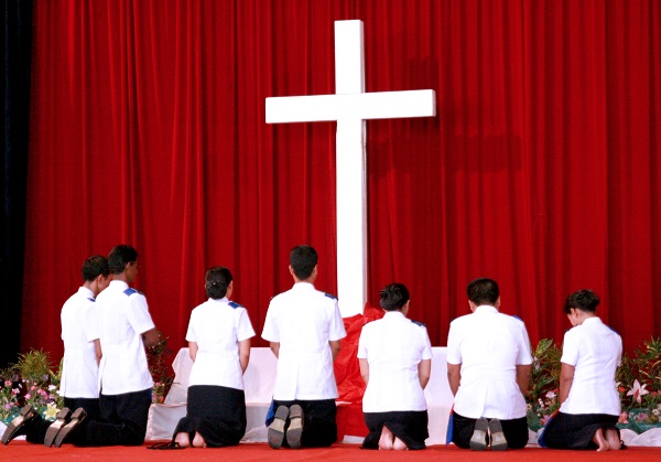 Newly commissioned lieutenants in Myanmar kneel at the foot of the cross to pray