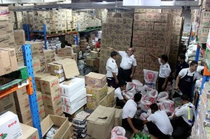 Colonel Wayne Maxwell, Lt-Colonel Alex Genabe, Secretary for Programs, and Major Reynaldo Magat at the SM warehouse in Manila with employees preparing seven tons of food for dispatch to Tacloban