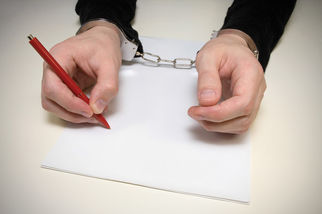 Image of someone writing a note in handcuffs