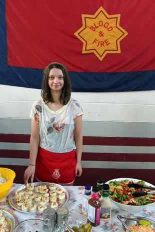 A young woman serves dinner at the Army's community supper