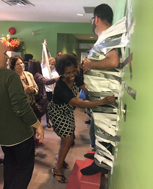 A member of Cornerstone CC in Mississauga, Ont., helps tape Cpt Jeff Arkell to the wall as a fundraiser for Partners in Mission