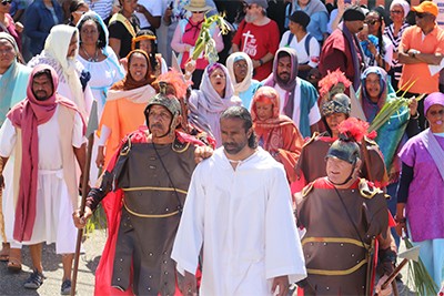 An actor playing Jesus walks through a crowd of people