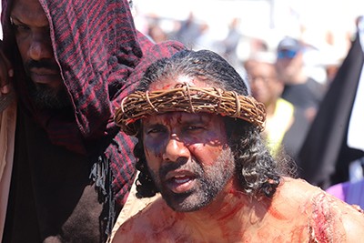 An actor playing Jesus wears a crown of thorns
