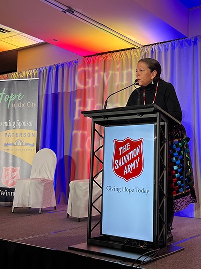 Tracy speaks behind a podium at Hope in the City