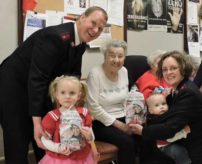 Captains David and Laura Hickman, with their children, greet a nursing home resident