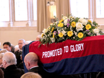 The coffin is taken to the front of the assembly hall