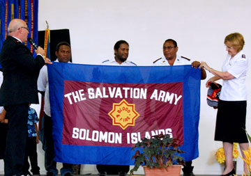 Commissioners Raymond and Aylene Finger present a new Salvation Army flag to the corps officers from the Solomon Islands, Captains Gandi and Muru Igoto