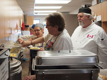 Volunteers assist chef Barry Tuomi in preparing lunch at the drop-in centre