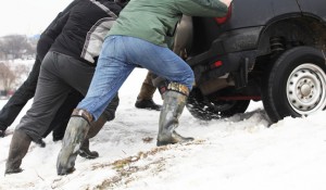 People attempt to push a car out of a snow bank