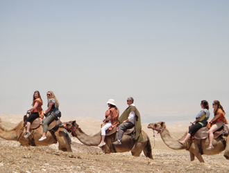 The group enjoys a camel ride through the desert hills