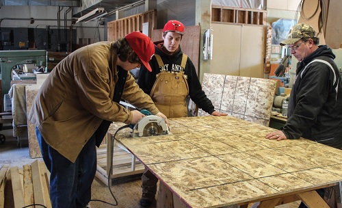 Eric Bertrand, Wolf Squires and Scott Concordia, program co-ordinator, cut wood to build doghouses