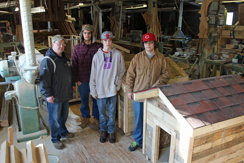 The group shows off their progress on several doghouses at the furniture workshop
