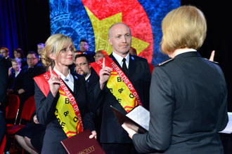 Newly commissioned Lts Rosalyn and Stephen Toynton salute Commissioner Susan McMillan