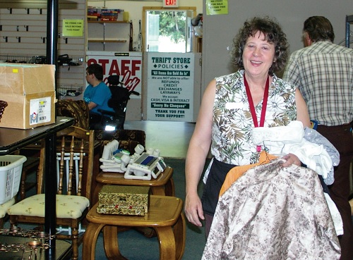 Angela Benoit, thrift store manager, helps stock items on the shop floor.