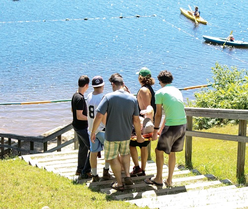 Staff and friends carry Dion Oxford down a steep hill to the lake at Camp Koinonia