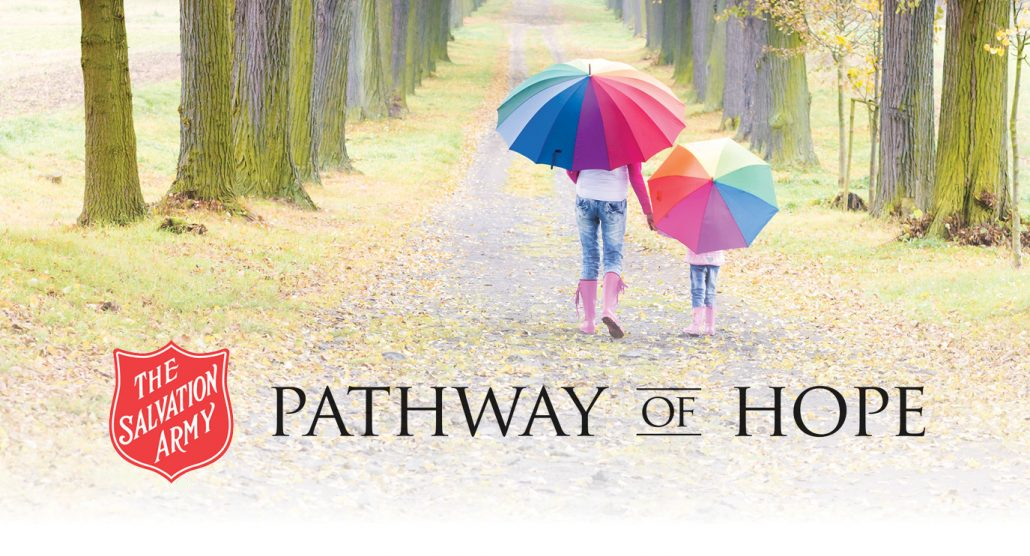 Image of parent and child holding rainbow coloured umbrellas while walking away down a tree lined path.