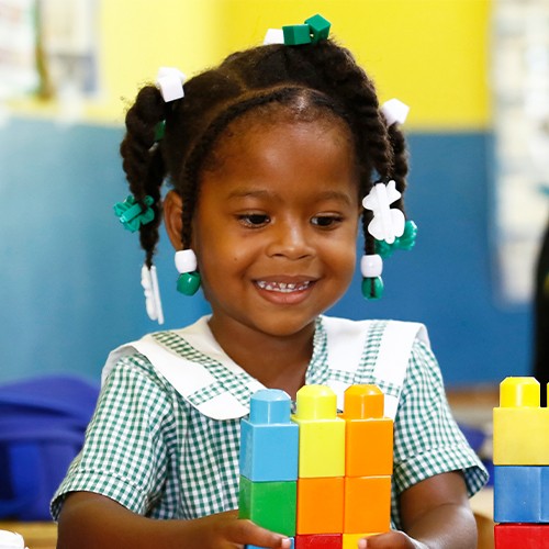 A young girl joyfully smiles as she engages in play with colorful Lego blocks.