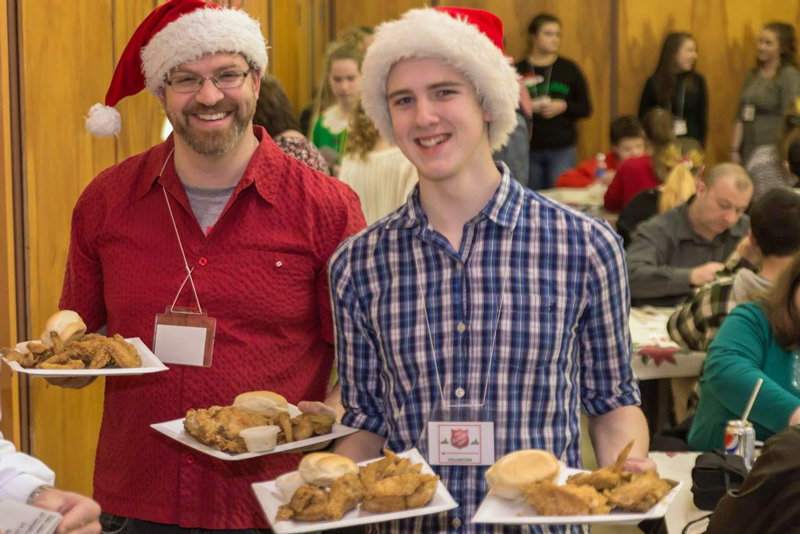 Two volunteers show off the main course at the Christmas supper hosted by St. John's Temple
