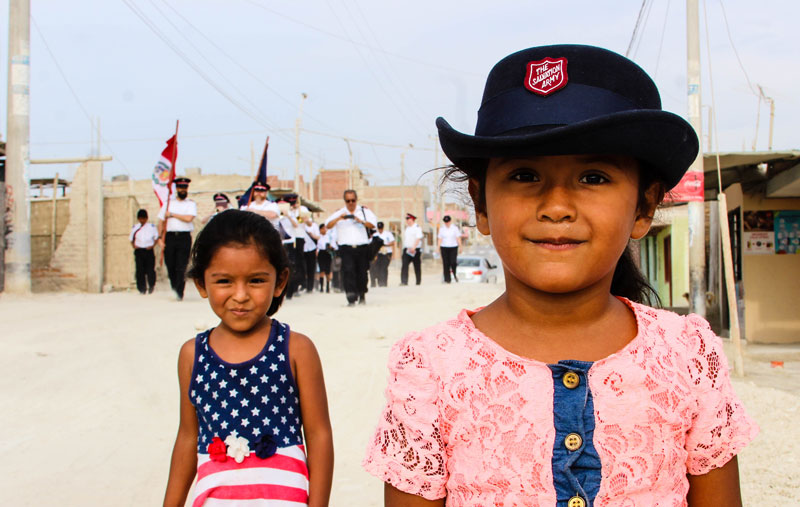 In Peru, a young girl wears a cadet’s hat with pride as she joins a march of witness
