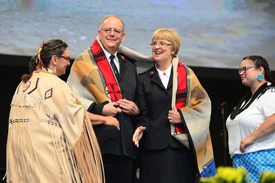 Indigenous officers wrap the General and Commissioner Cox in a traditional blanket