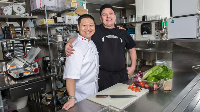Paul Wessel (right) shares a laugh with Alvin Chong, Belkin House’s food services manager