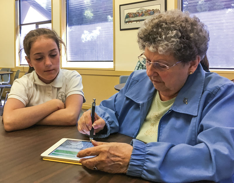 Powell River Christian School student Hillary English teaches Eva Bella how to use an iPad