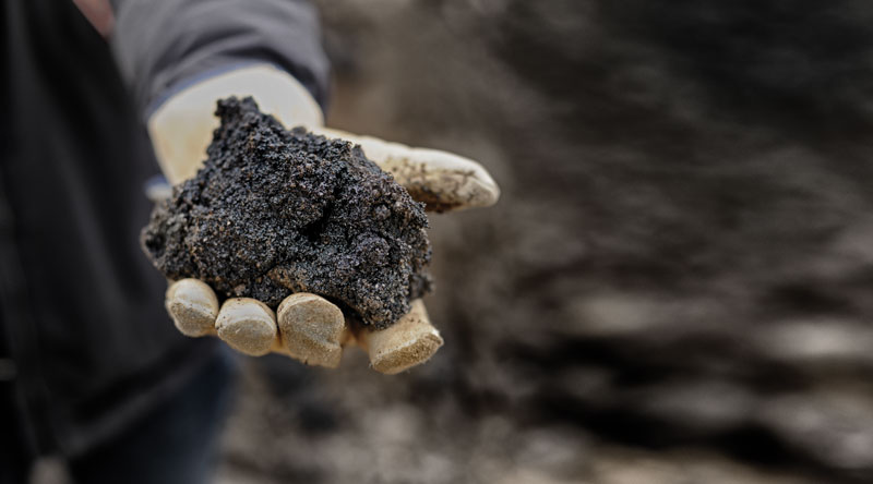 A worker holds Alberta oilsand (Photo: © francisblack/iStock.com)