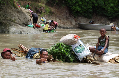 Papua New Guineans float “garden foods” down the river to be sold at the market