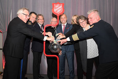 A group of people put donations in a Salvation Army kettle