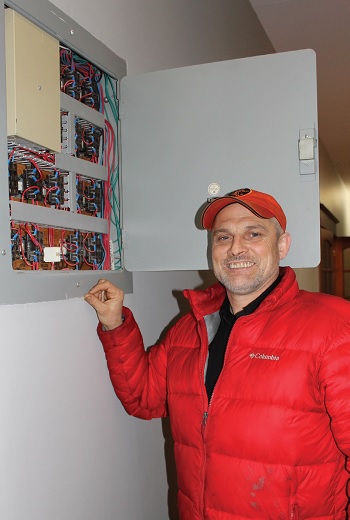 Jim Skinner poses in front of an electrical box at his place of work