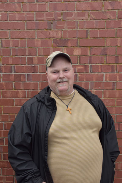 Brian Ingersoll stands by a brick wall