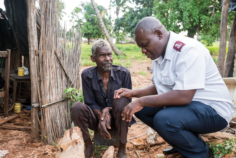 Mjr José Nharugue prays with a man who lost his home after a cyclone.