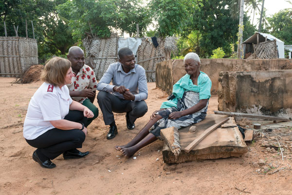 Three Salvation Army personnel speak to a woman whose home was destroyed by a cyclone