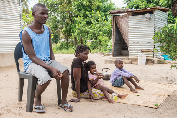 A family of two parents and two children sit outside