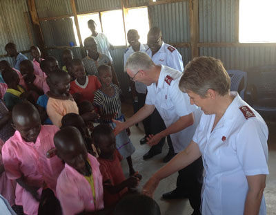 Photo of Lt-Cols Morris and Wanda Vincent shaking hands with children