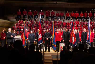 General Brian Peddle prays as bandmasters gather at the front of the stage