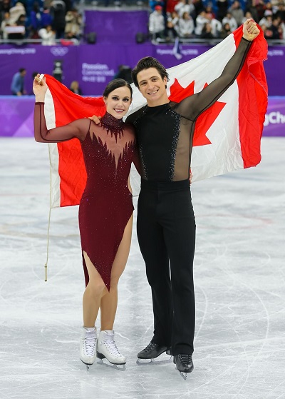 Tessa Virtue and Scott Moir proudly holding the Canadian flag at the 2018 Olympic Games