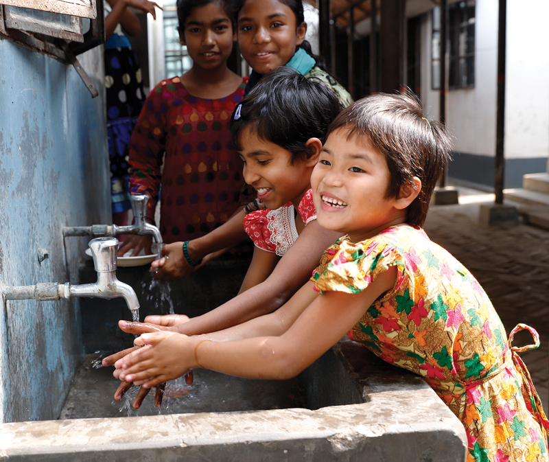 A young girl washes her hands in Bangladesh.