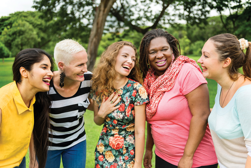 A diverse group of woman laugh together