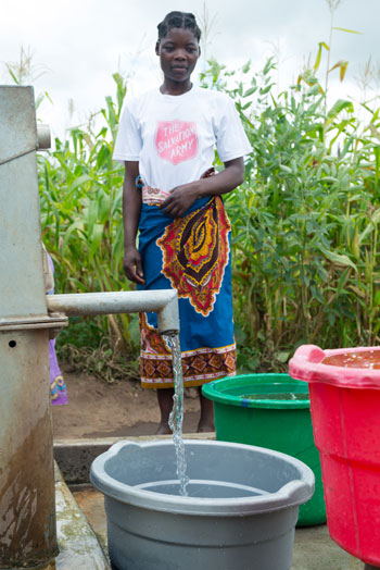 Malawi Salvation Army member drawing clean water from a bore hole