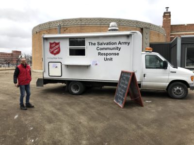 A team member stands in front of a Salvation Army emergency vehicle.