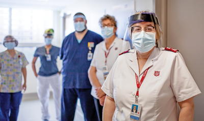 Photo of Mjr Marie Hollett standing in hallway with hospital staff in the background