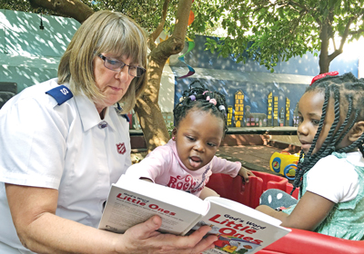 Photo of Debbie Clarke reading with young children