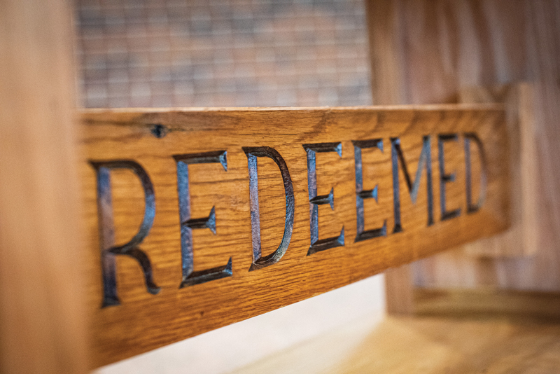 A piece of wood engraved with the word "Redeemed."