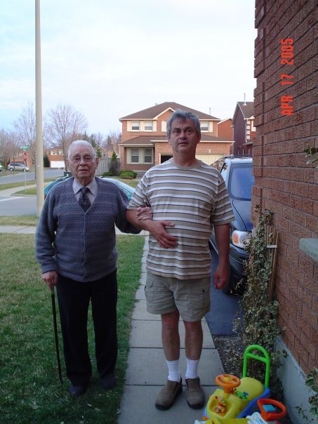 Major Ross H. Cole holds his son Oren Cole's arm outside next to a house.