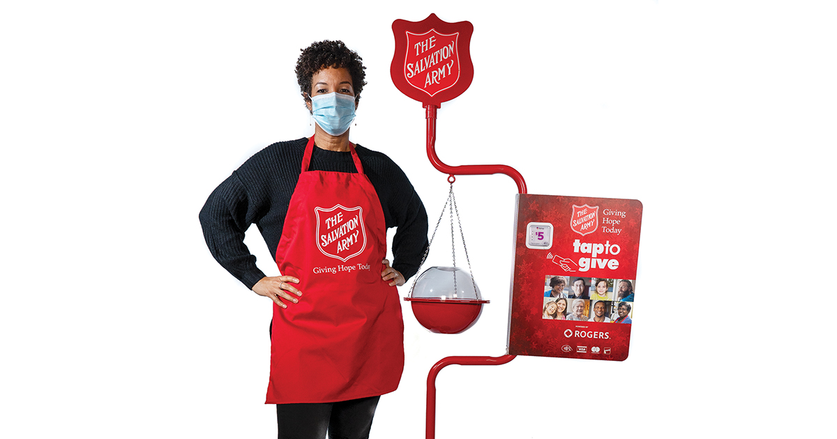 A volunteer wearing a mask stands beside a kettle.