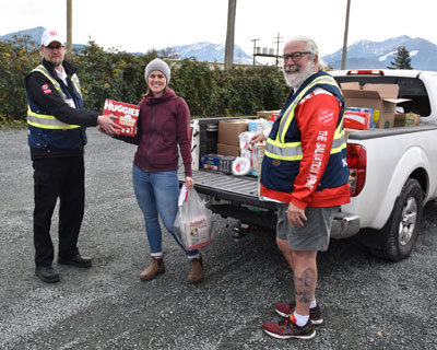 Three people load a truck with supplies