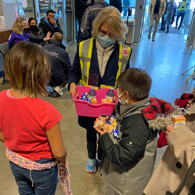 A woman hands out snacks to two children