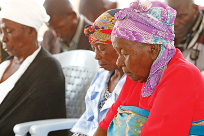 Residents at Mitanda bow heads in prayer during morning devotion