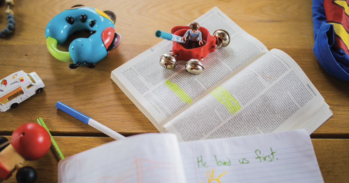 A bible, children's toys and a note that reads "He loved us first" in a child's handwriting